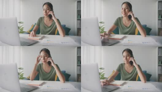 亚洲商务女性，穿着休闲服装，在家中客厅用笔记本电脑和手机咨询客户。高清在线视频素材下载