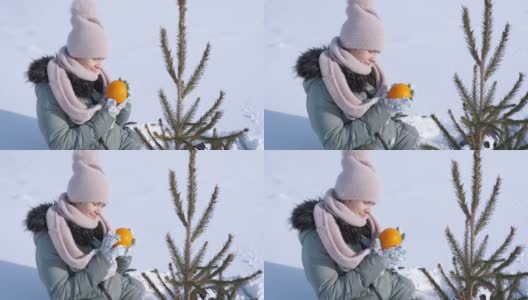 冷杉树旁的孩子带着橘子。高清在线视频素材下载