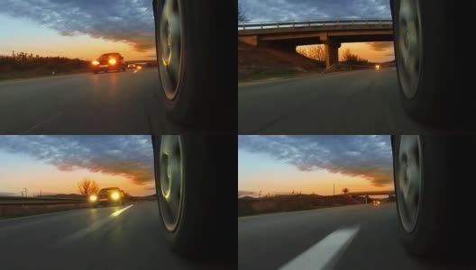 在乡村道路上行驶的跑车与车辆灯从对面的汽车日落。车轮旋转POV -观点，日出高清在线视频素材下载
