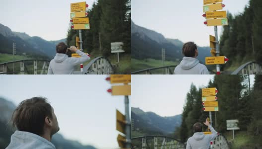 男子退后在旅游路标选择指向目的地的自然近距离慢动作。在瑞士或德国的旅行者在决定去哪里时，会显示乡村地名高清在线视频素材下载