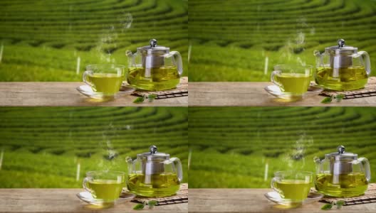 一杯热腾腾的绿茶和玻璃罐和绿茶在木桌和茶园的背景高清在线视频素材下载