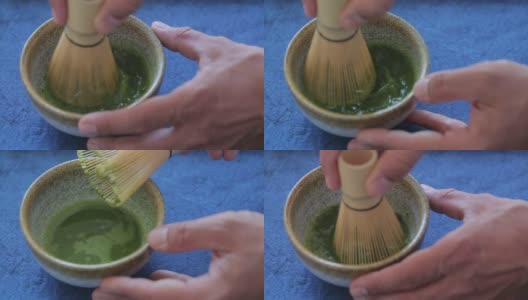 男人在一个碗里准备抹茶在蓝色的表面。饮料是抗氧化剂和多酚的丰富来源。高清在线视频素材下载