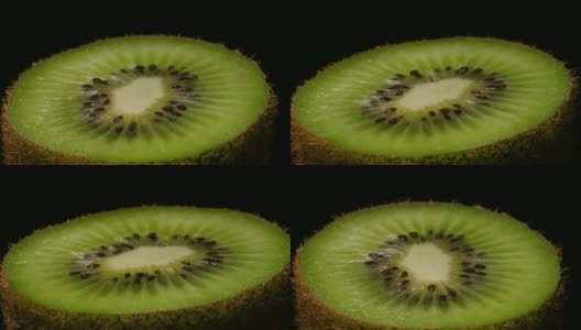 猕猴桃在转盘上旋转的微距拍摄。一个多汁的绿色猕猴桃切成两半，孤立在黑色背景上的特写。高清在线视频素材下载
