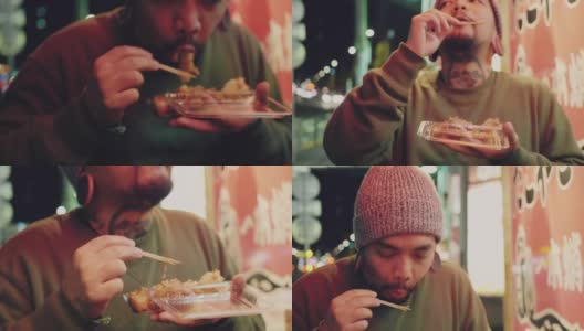 亚洲游客男子晚上在东京街头吃东西。高清在线视频素材下载