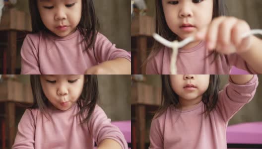 亚洲小女孩有乐趣吃面条在塑料杯在家里。垃圾食品的概念。高清在线视频素材下载