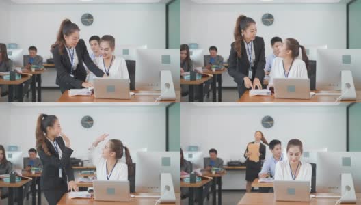 亚洲女商人经理在现代商务办公桌上用电脑与年轻的女同事或新员工讨论信息。高清在线视频素材下载