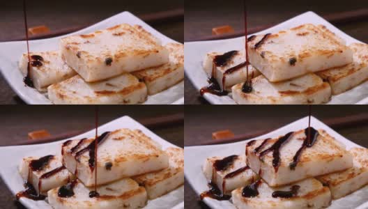 在餐厅将黑酱油倒在即食的美味萝卜糕上，这是中国传统的地方菜萝卜糕。高清在线视频素材下载