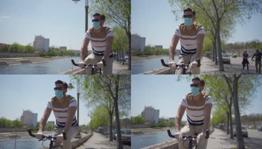 年轻人骑自行车独自在城市海滨，应用所有的保护措施和社会距离在大流行期间高清在线视频素材下载