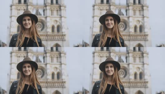 一幅年轻美丽的女人戴着帽子站在巴黎圣母院附近的肖像，法国看着镜头高清在线视频素材下载