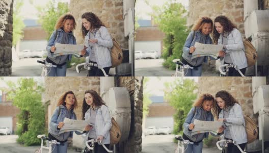 慢动作的漂亮女孩游客看着地图和说话站在大街上的外国城市与自行车。自行车旅游、出国旅游和人的概念。高清在线视频素材下载