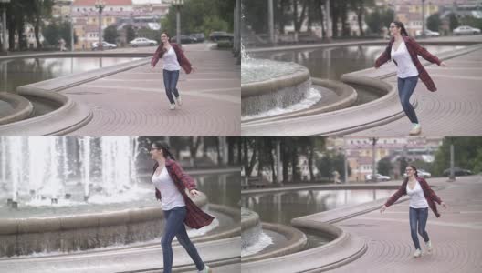 快乐女孩在城市公园附近的喷泉嬉戏，蹦蹦跳跳跑着幸福生活高清在线视频素材下载