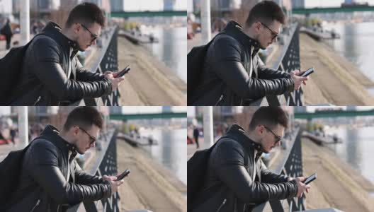 一个年轻人在城市的河边用手机发短信高清在线视频素材下载