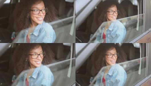 快乐的年轻微笑的非洲裔美国女人黑头发戴眼镜的司机坐在新的棕色汽车，微笑着看着相机享受旅程。驾驶课程和人寿保险概念高清在线视频素材下载