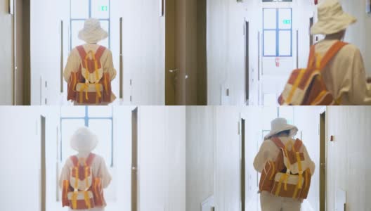 亚洲女性留着短发，戴着帽子，提着一个橙色的包走在公寓的走廊里，以开朗快乐的态度外出度假旅游和自由的理念高清在线视频素材下载