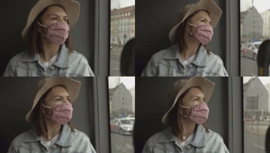 一名戴着防护面具的年轻女子坐在公交车上，看着窗外闪烁的城市风景高清在线视频素材下载