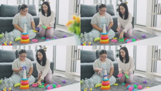 一位患有唐氏综合症的年轻女子和小女孩在家里玩耍高清在线视频素材下载