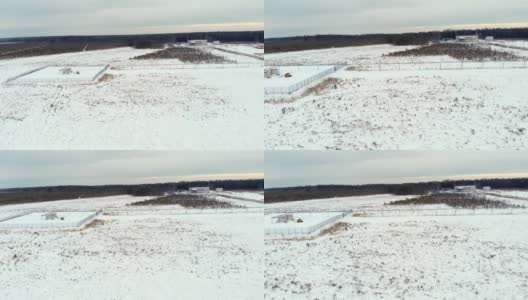 一架无人机在该国北部工业区的积雪覆盖地区上空飞行。一辆小型拖拉机装载机用设备清理建筑物附近的积雪高清在线视频素材下载