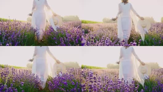 穿着白色连衣裙的女人走在薰衣草的田野里高清在线视频素材下载