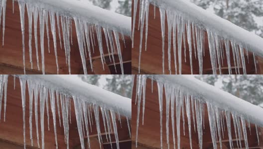在冬季森林的某个地方，长长的冰柱悬挂在木屋的屋顶上高清在线视频素材下载