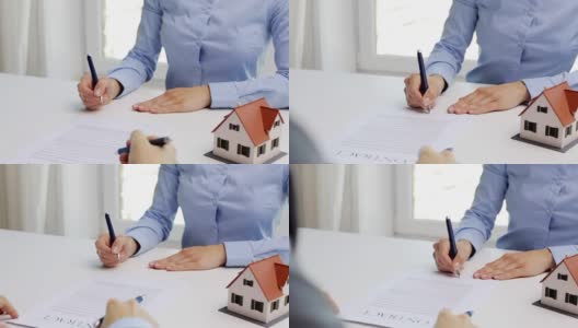 商人和女商人与房屋模型签署文件和握手在办公室高清在线视频素材下载