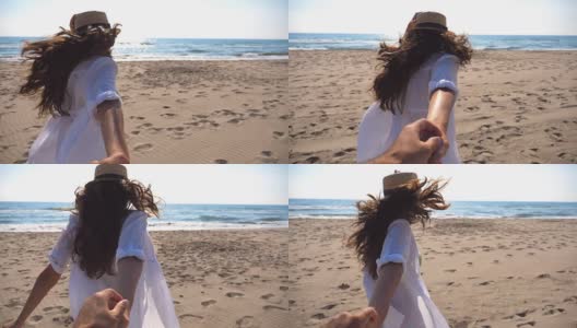 一个面目全非的女孩牵着一个男人的手在海滩上奔向大海。跟着我拍的年轻女子戴着帽子拉她的男朋友在海边。暑假或假日概念。观点慢动作高清在线视频素材下载