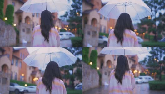 亚洲年轻女子走在下雨的街道伞下。高清在线视频素材下载
