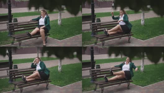 宽镜头疲惫疲惫肥胖的白种女商人坐在长凳上伸腿叹息。成年大号女人的肖像休息在城市户外。生活平衡和生活方式。高清在线视频素材下载