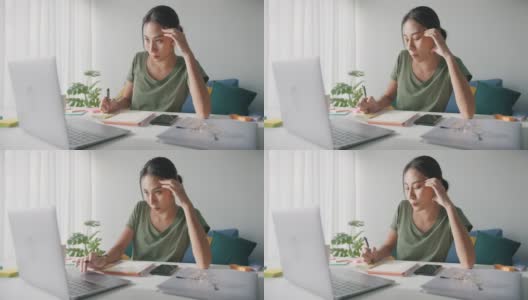 疲倦的年轻亚洲商业妇女在休闲工作笔记本电脑在客厅在家里。高清在线视频素材下载