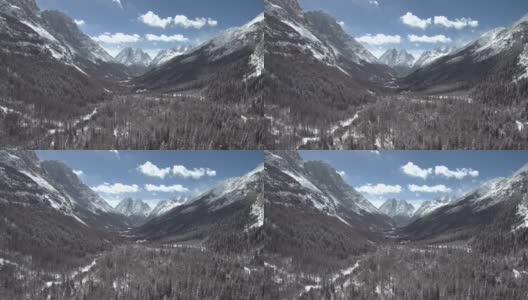 无人机飞行在高海拔山谷(双桥)与蓝天，雪林，山的背景高清在线视频素材下载