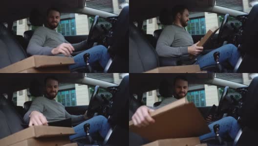 快递员拿着装着披萨的纸箱离开汽车，从下面射击。高清在线视频素材下载