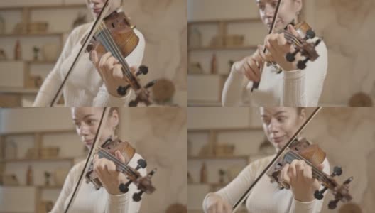 年轻的金发女人拉小提琴的特写，极简主义的家庭内部高清在线视频素材下载