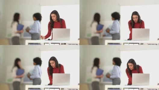 西班牙女商人在笔记本电脑和同事在后台工作高清在线视频素材下载