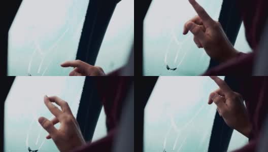 一个人用一根手指在车窗上画画。外面下雨的天气。滴高清在线视频素材下载