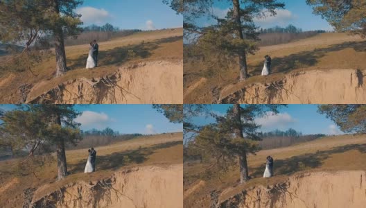 一对年轻美丽的新婚夫妇一起站在山坡上。结婚的那一天。空中拍摄高清在线视频素材下载