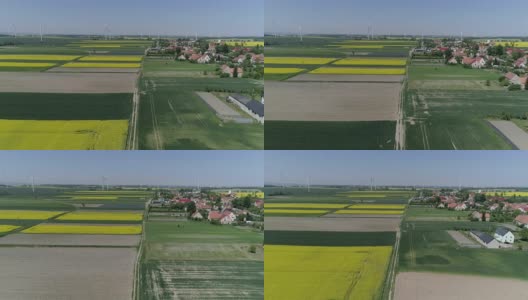 鸟瞰图风力涡轮机和农田在一个春日附近的村庄在慢镜头高清在线视频素材下载