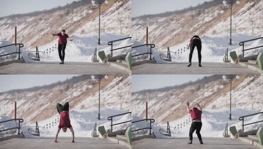 年轻肌肉发达的杂技演员在冬季的道路上双手站立和保持平衡的侧面图高清在线视频素材下载