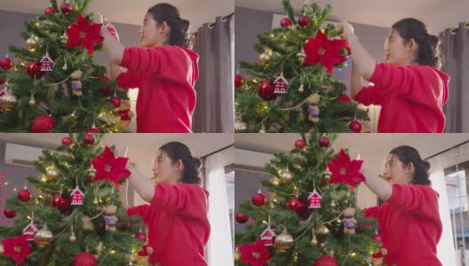 近距离亚洲少女享受装饰圣诞树在家里的客厅在圣诞节的假期。美女挂红球。高清在线视频素材下载