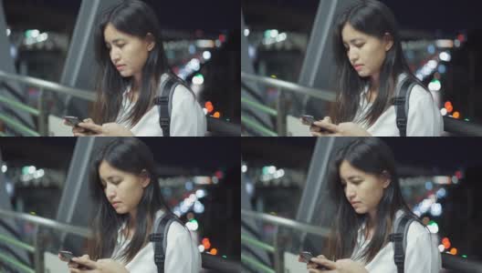 泰国一名年轻女子晚上站在走廊上使用智能手机。高清在线视频素材下载