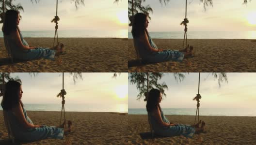 亚洲美女坐在海边的秋千上与夕阳背景在周末假期。快乐独自旅行的概念。4 k慢动作。高清在线视频素材下载