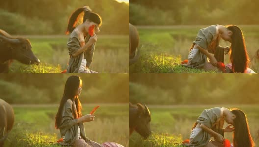 美丽的亚洲女人的肖像坐在傍晚与温暖的照明日落的田野。高清在线视频素材下载
