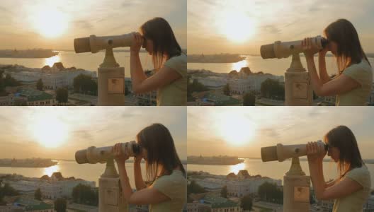 年轻女子透过旅游望远镜，在夕阳下探索城市高清在线视频素材下载