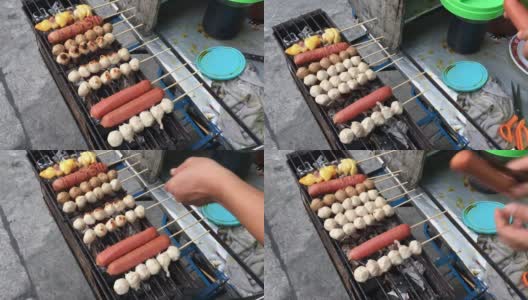 泰国街头小吃市场，摊贩的手在木炭炉上烤着肉丸、猪肉丸子和香肠。烹饪概念。视频片段。高清在线视频素材下载