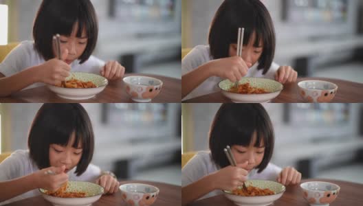 一个亚洲华裔的小女孩在家做了面条，在餐厅用筷子吃高清在线视频素材下载