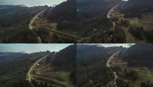鸟瞰图的绿色松林在高山峻岭无人机飞行以上的道路高清在线视频素材下载