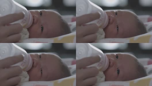 可爱的亚洲新生女婴正在吸奶瓶里的奶。母亲给新生儿喂奶。高清在线视频素材下载