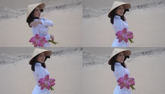 美丽的越南人捧着粉红莲花在白色沙丘沙漠上行走的4K电影，越南高清在线视频素材下载