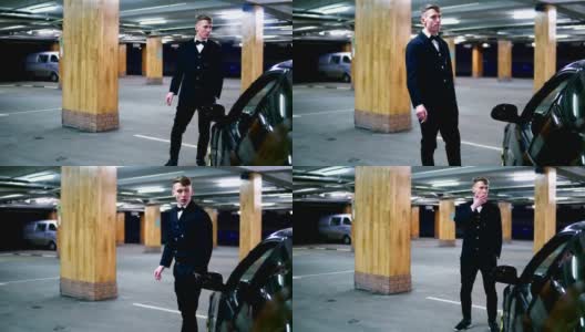 一个穿着黑色西装打着领结的年轻人在停车场的黑色汽车旁抽着烟。一走了之高清在线视频素材下载