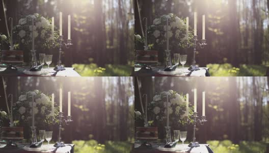 近距离的白色复古烛台上的婚礼装饰表在森林。背景是一束白玫瑰。森林里的浪漫晚餐高清在线视频素材下载