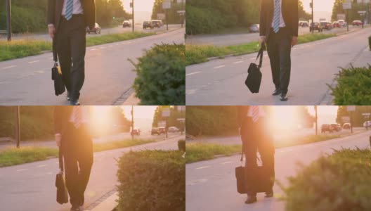 低角度:在日落时分，一个穿西装的男人走在街上。高清在线视频素材下载