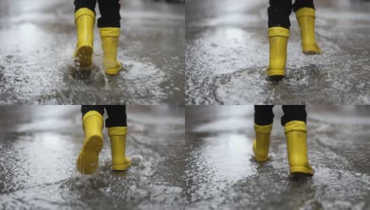 穿着黄色橡胶靴子的孩子的腿在水坑里跳高清在线视频素材下载